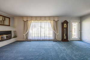 Unfurnished living room featuring crown molding and carpet flooring