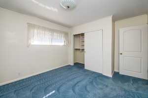 Unfurnished bedroom featuring a closet, crown molding, and dark colored carpet