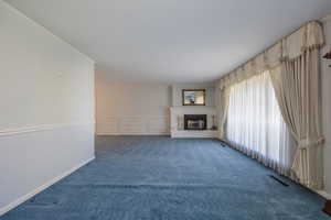 Unfurnished living room with carpet flooring, ornamental molding, and a fireplace