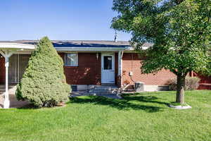 Rear view of house with a lawn and central AC unit