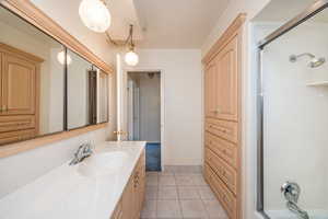 Bathroom with walk in shower, ornamental molding, tile patterned flooring, and vanity