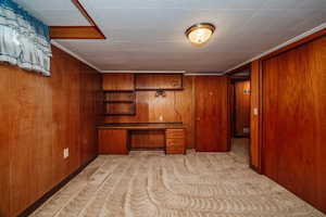 Carpeted office space with wooden walls and built in desk