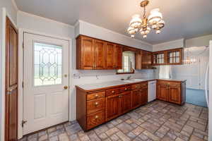 Kitchen featuring hanging light fixtures, sink, white dishwasher, and a notable chandelier