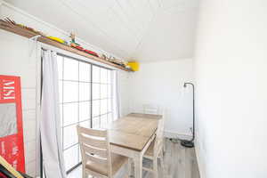 Dining area with vaulted ceiling and light hardwood / wood-style flooring