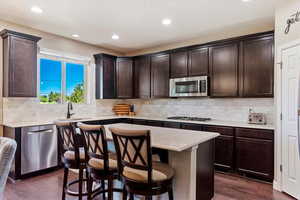 Kitchen with a center island, dark wood-type flooring, stainless steel appliances, and sink