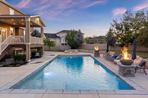 Pool at dusk with a patio and a fire pit