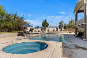 View of swimming pool with an in ground hot tub and a patio area