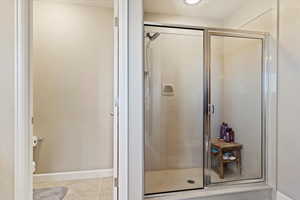 Bathroom with a textured ceiling, tile patterned flooring, and a shower with door