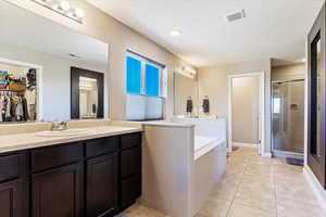 Bathroom with shower with separate bathtub, tile patterned flooring, a textured ceiling, plenty of natural light, and vanity