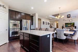 Kitchen with dark hardwood / wood-style floors, hanging light fixtures, a center island, and stainless steel appliances