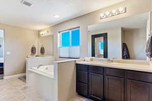 Bathroom with vanity, a bathing tub, a textured ceiling, and tile patterned floors