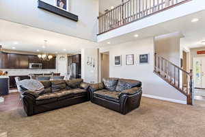 Living room with a high ceiling, carpet flooring, and a chandelier