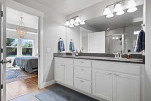 Bathroom featuring wood-type flooring, a textured ceiling, an inviting chandelier, walk in shower, and vanity