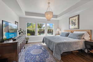 Bedroom with wood-type flooring, a chandelier, and a tray ceiling