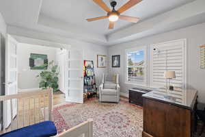 Interior space with light hardwood / wood-style flooring, a tray ceiling, ceiling fan, and a nursery area