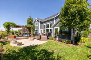 Back of house featuring an outdoor living space with a fire pit, a deck, and a yard