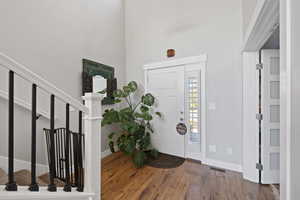 Foyer entrance with hardwood / wood-style flooring and a towering ceiling