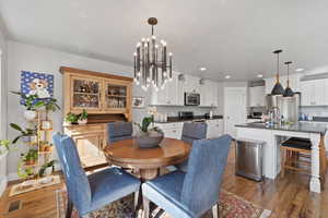 Dining area featuring sink, dark wood-type flooring, and a notable chandelier