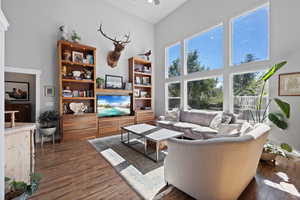 Living room featuring a high ceiling, ceiling fan, and dark wood-type flooring