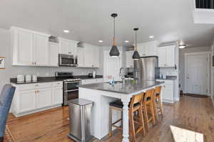 Kitchen with light hardwood / wood-style flooring, stainless steel appliances, white cabinets, and sink