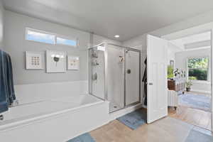 Bathroom featuring a textured ceiling, wood-type flooring, and separate shower and tub