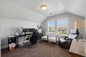 Carpeted office with a textured ceiling and lofted ceiling