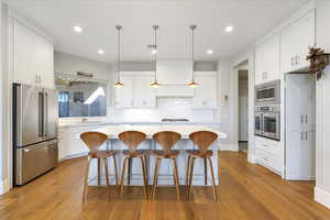 Kitchen with stainless steel appliances, white cabinets, and light wood-type flooring