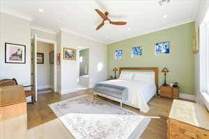 Bedroom with light hardwood / wood-style flooring, ceiling fan, ensuite bathroom, and ornamental molding