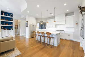 Kitchen featuring white cabinets, high end fridge, a center island, and light hardwood / wood-style flooring