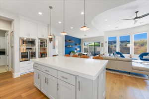 Kitchen with light wood-type flooring, a kitchen island, and white cabinets