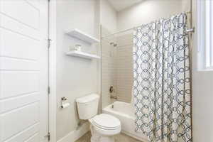 Bathroom featuring tile patterned floors, toilet, and shower / bath combo