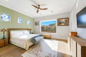 Bedroom with light wood-type flooring, crown molding, and ceiling fan