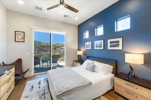 Bedroom with multiple windows, access to outside, wood-type flooring, and ceiling fan