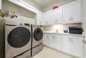 Laundry area with cabinets, independent washer and dryer, and sink