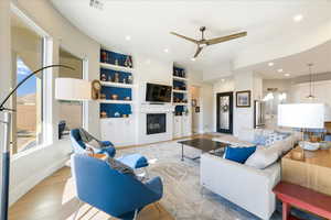 Living room with a fireplace, ceiling fan, light hardwood / wood-style flooring, built in shelves, and sink