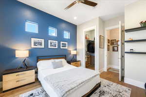 Bedroom featuring a closet, ceiling fan, a walk in closet, and light hardwood / wood-style flooring