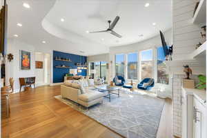 Living room with a fireplace, ceiling fan, light hardwood / wood-style flooring, and a wealth of natural light