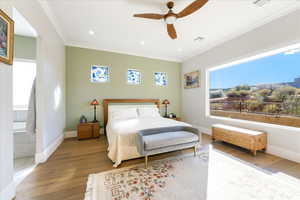 Bedroom with wood-type flooring, ensuite bath, ceiling fan, and crown molding