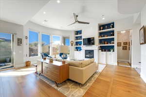 Living room with light hardwood / wood-style flooring, ceiling fan, a fireplace, and built in features