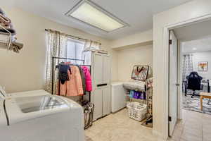 Laundry area featuring light tile patterned floors, washing machine and clothes dryer, and cabinets