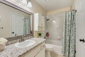 Full bathroom with shower / tub combo with curtain, tile patterned flooring, vanity, and toilet