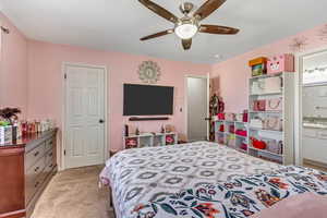 Bedroom with light colored carpet, ceiling fan, and ensuite bathroom