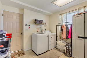 Washroom with light tile patterned floors and washing machine and clothes dryer