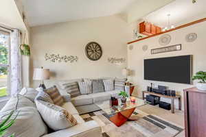 Living room with light carpet, beam ceiling, and high vaulted ceiling