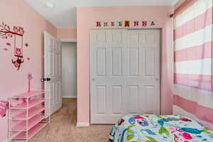 Bedroom with light carpet and a closet