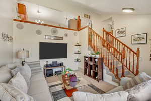 Living room featuring carpet floors, vaulted ceiling, and a notable chandelier