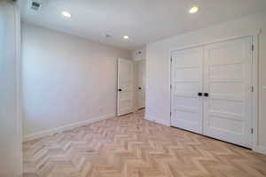 Unfurnished bedroom featuring light parquet floors and a closet