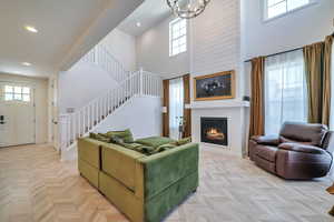 Living room featuring light parquet flooring, a high ceiling, and a chandelier