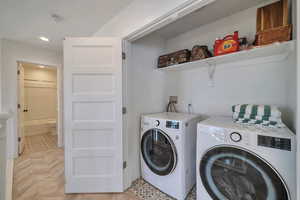 Laundry room with light parquet flooring and washing machine and clothes dryer