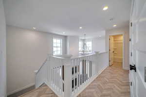 Hallway with an inviting chandelier and light parquet floors